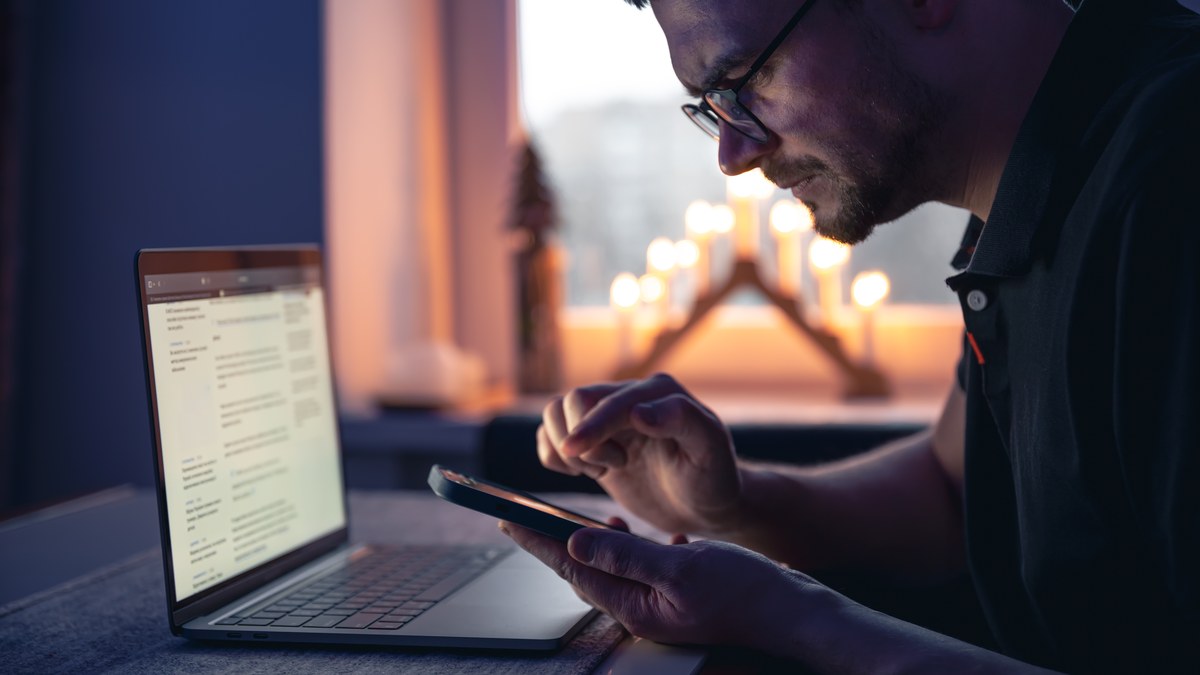 A person inspecting url links on a laptop and smartphone screen late at night