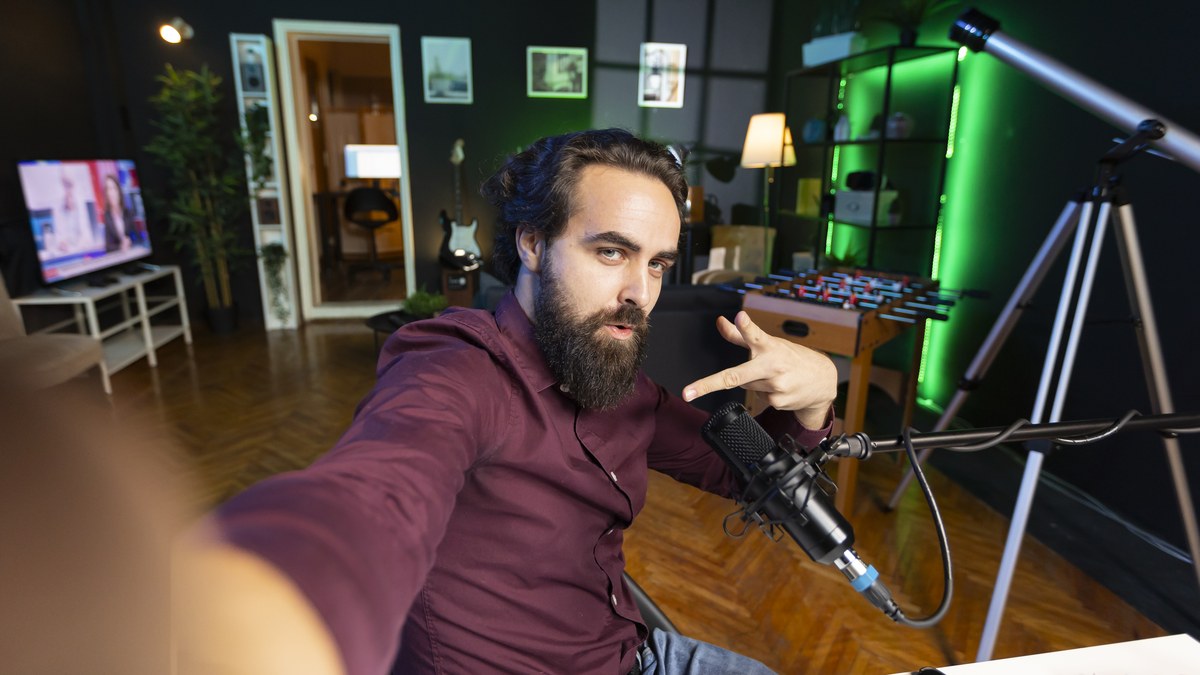 Gaming broadcaster in front of microphone and dual monitors during an active live stream