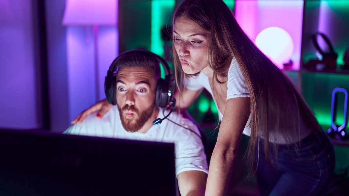 A young couple playing computer video games together in a gaming room