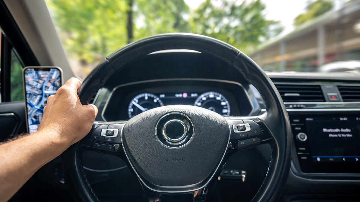 A driver using smartphone GPS map navigation mounted on car dashboard