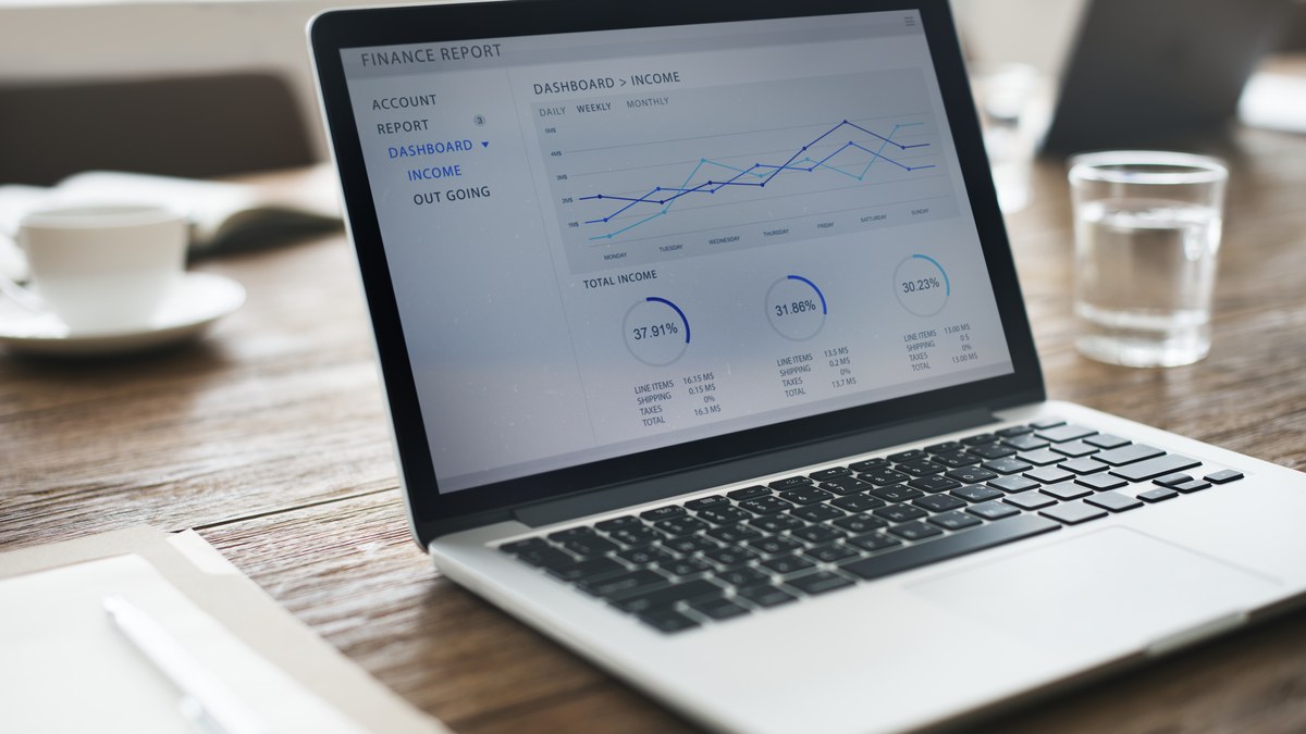 Data analyst reviewing multi-platform link click analytics charts on desktop monitor and tablet