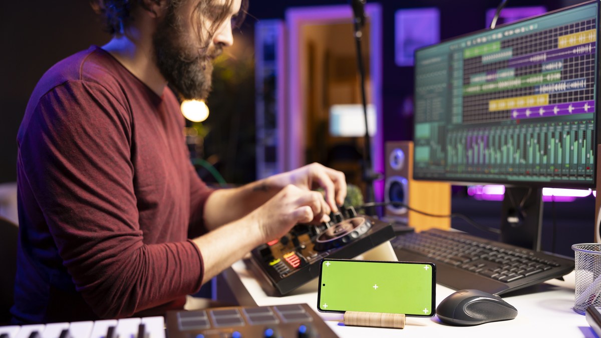 Musician working on audio console with smart link hub displayed on smartphone screen