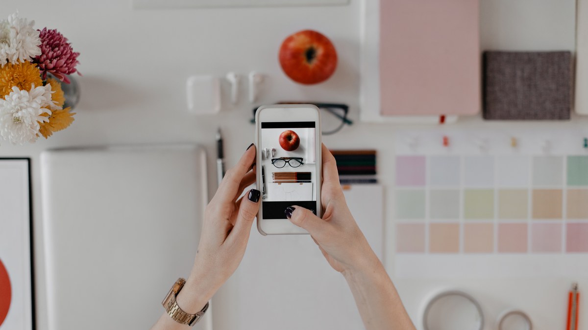 A flatlay of a smartphone surrounded by visual design stationery and aesthetic mood board materials