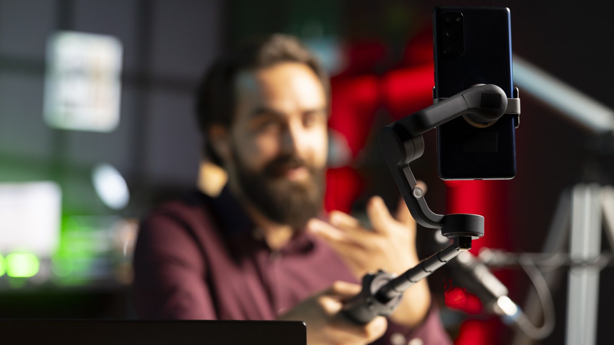 Smartphone displaying TikTok video feed alongside YouTube studio subscriber growth metrics