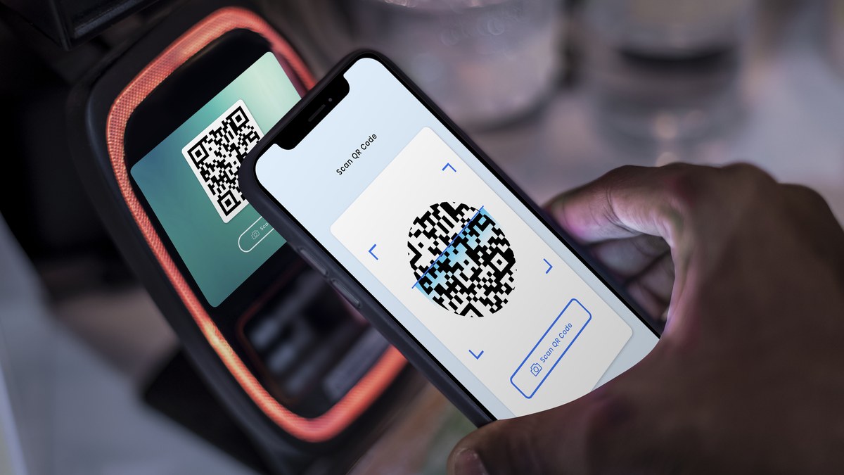 Customer pointing smartphone camera at a stylized printed table QR code stand in a modern venue