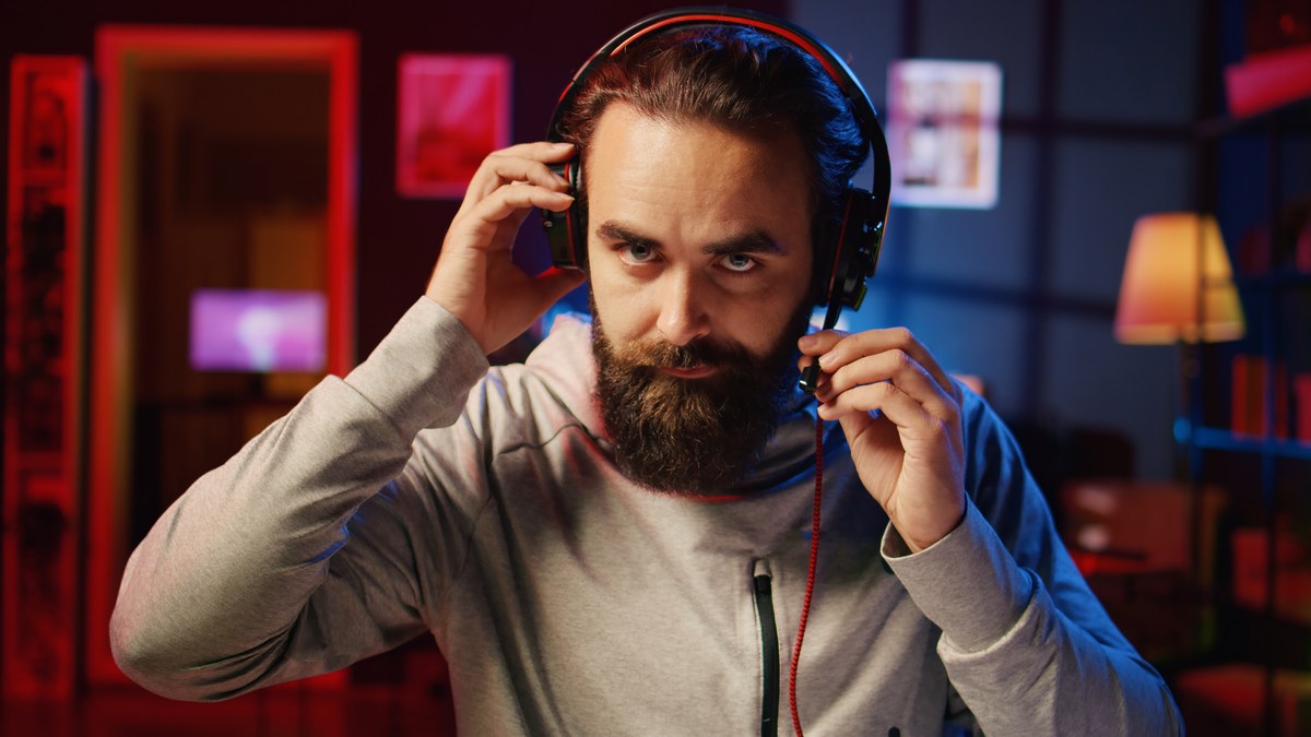 Musician with headphones in home recording studio reviewing streaming analytics on laptop and phone