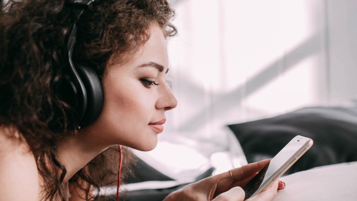 Smartphone headphones lying on desk with mobile screen showing Spotify web player instead of app