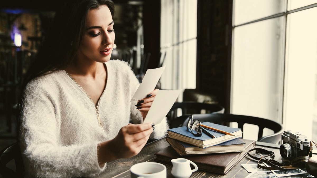 Writer sitting in a cafe reading a newsletter article on a tablet using the Substack mobile reader