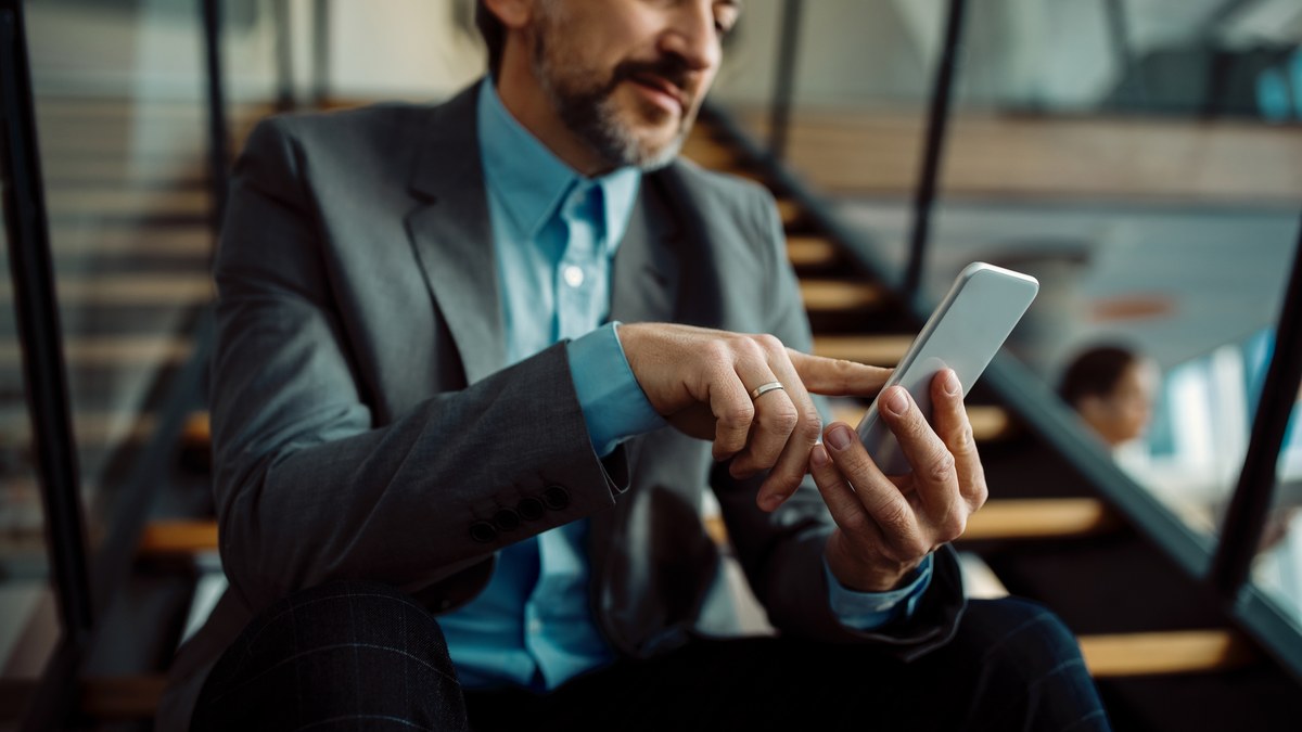 Close-up of businessman typing phone number into mobile phone messaging app on staircase