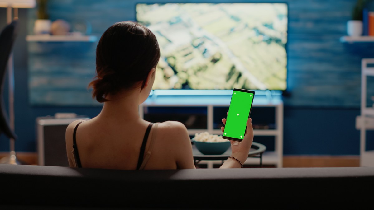Person holding mobile smartphone viewing video on screen