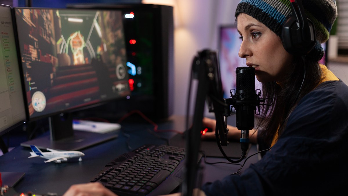 A female gamer live streaming computer video games with broadcast chat on monitor
