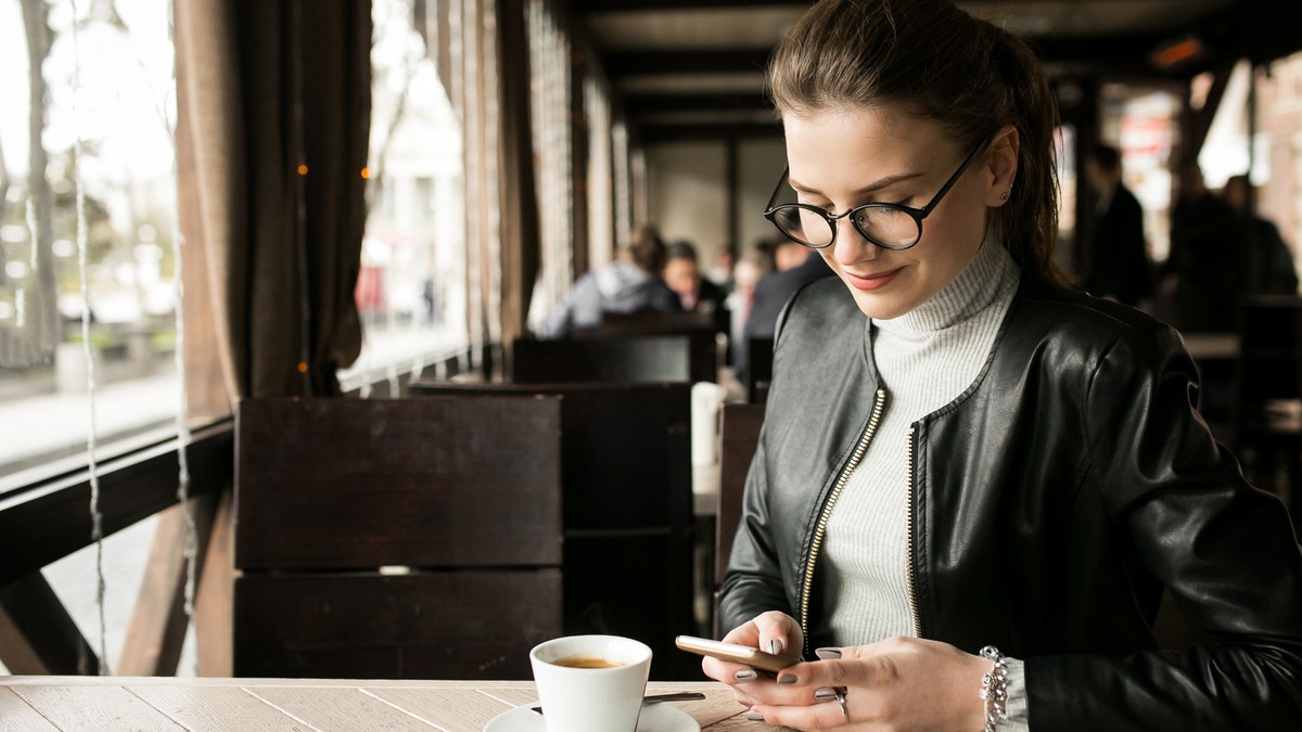 A business manager using a smartphone at a cozy restaurant dining table