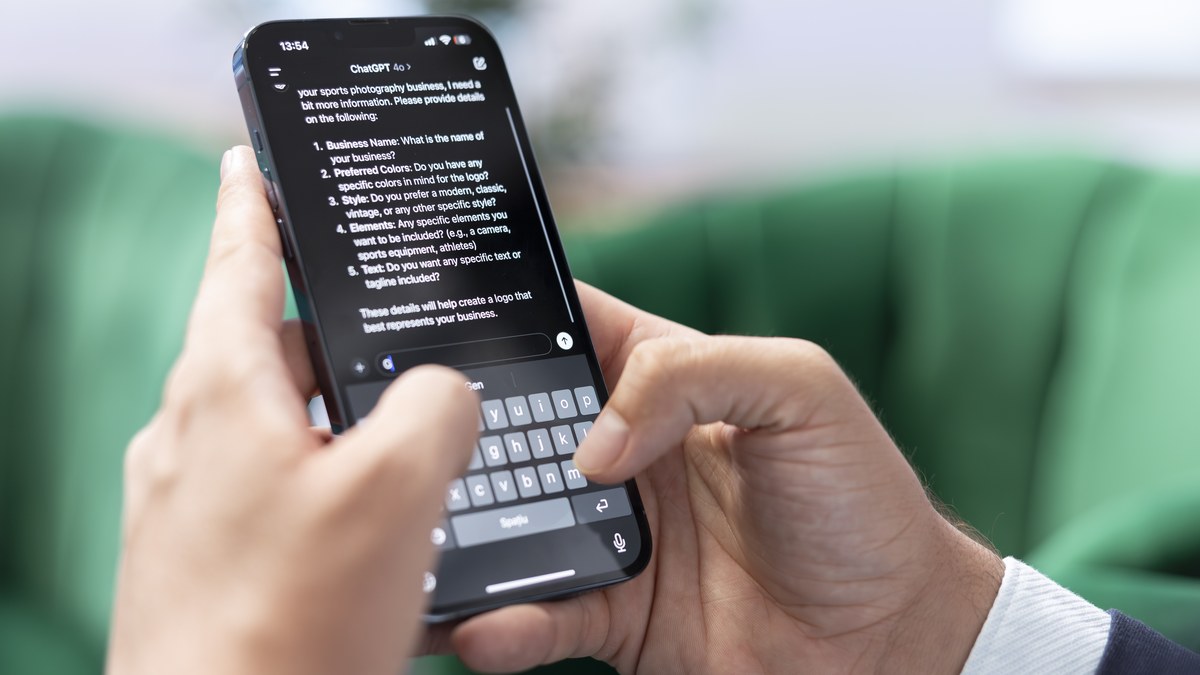 User holding mobile phone typing a prompt into messaging chat screen