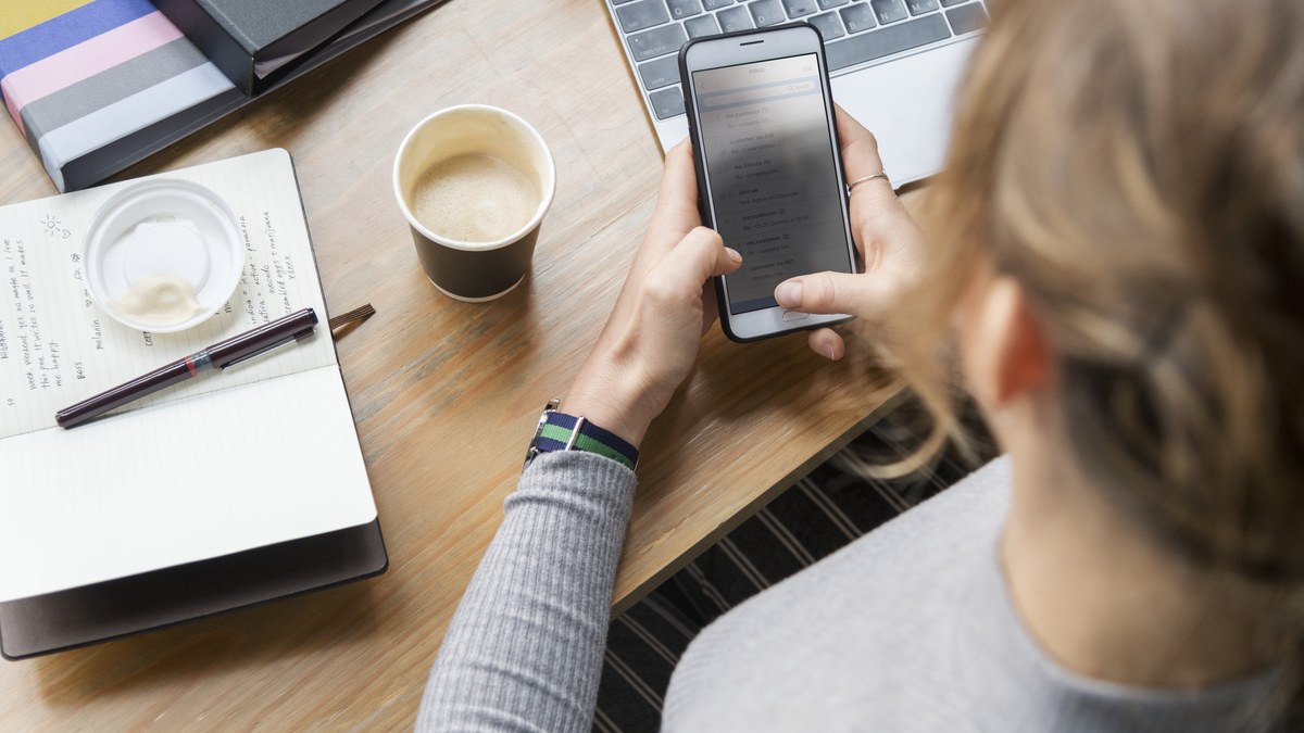 Woman sitting at desk texting customer message on mobile smartphone