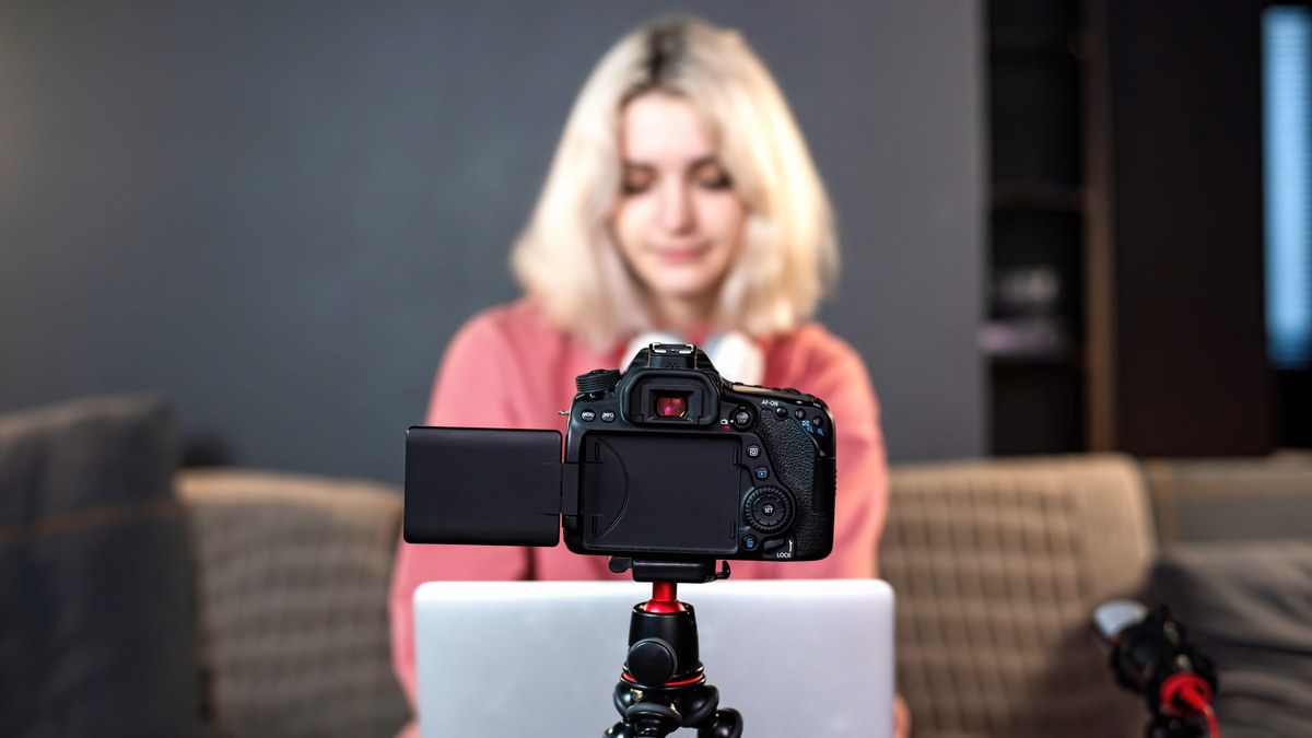 Content creator standing in front of studio equipment reviewing channel metrics on a laptop