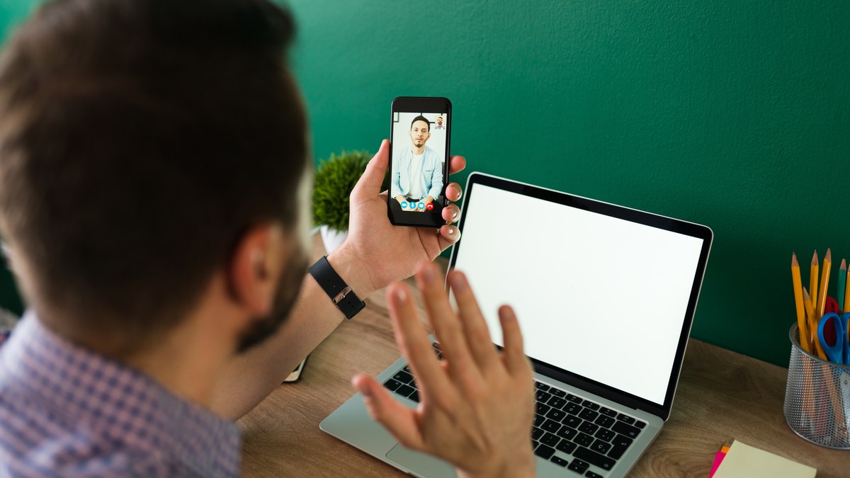 Person typing and pinning an engagement comment on a YouTube video using a laptop and smartphone