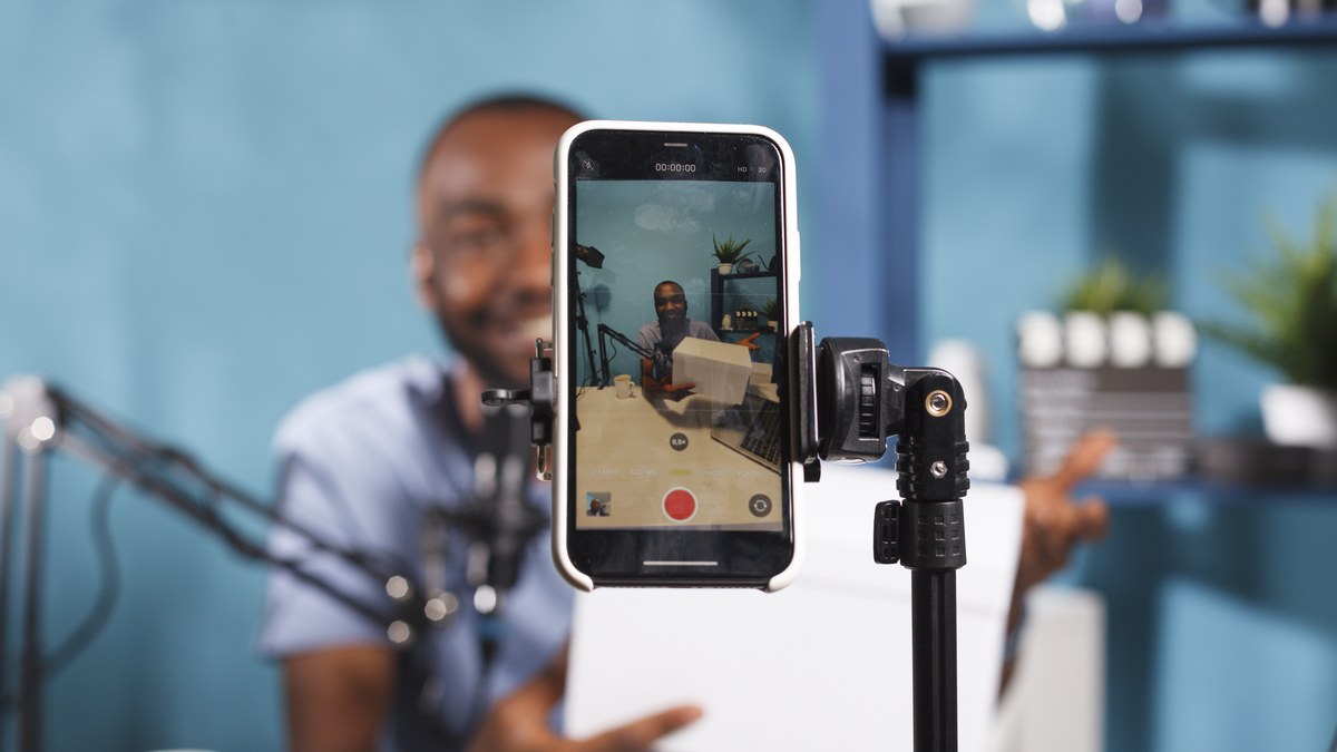 Content creator recording video on mobile phone on tripod